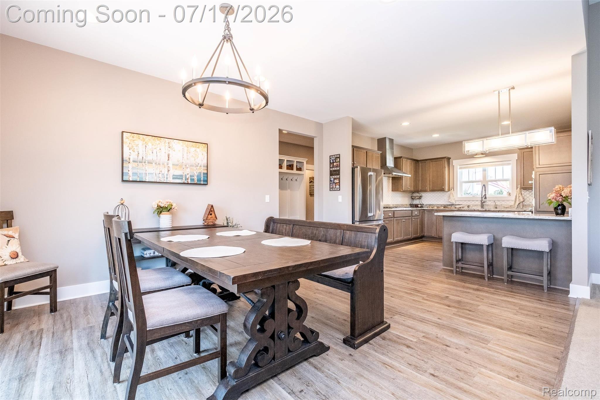 12349 Sugar Maple Drive Fenton, MI 48430 - Photo 12 of 67 Open-concept dining area featuring wood-finish flooring, a circular chandelier, and direct sightlines to the kitchen