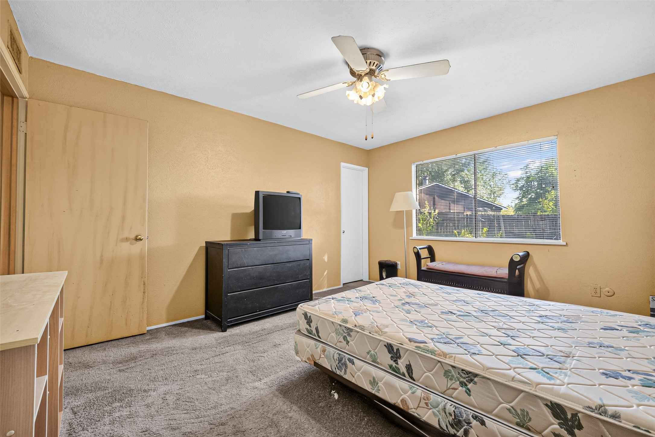 22926 Millgate Drive Spring, TX 77373 - Photo 25 of 34 This bedroom features neutral walls, a ceiling fan, and a large window for natural light. It includes a closet, dresser, and space for a bed, creating a cozy and functional space.