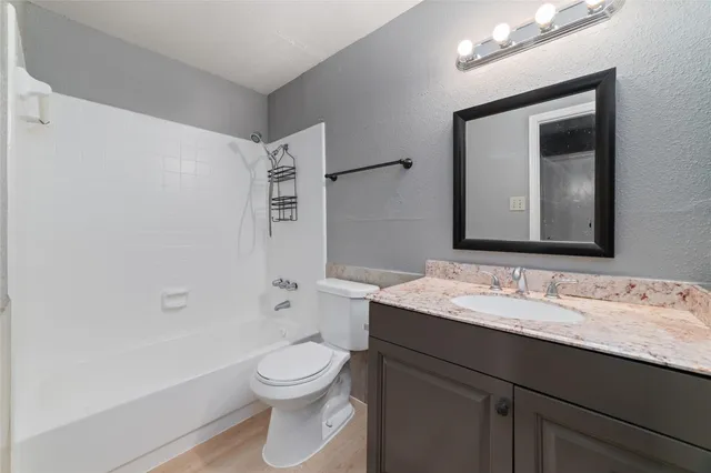 a bathroom with a granite countertop sink toilet a large mirror and shower