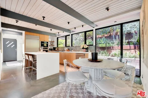 a kitchen with stainless steel appliances kitchen island granite countertop a table chairs in it and wooden floors