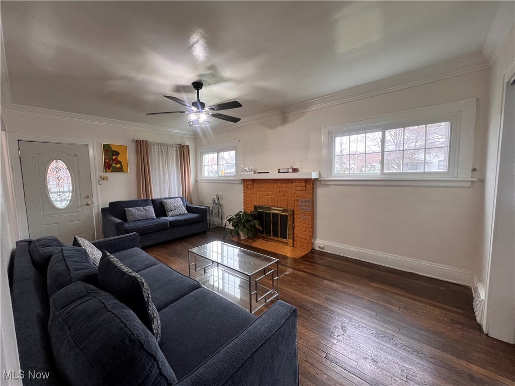 1686 Avalon Road Cleveland, OH 44112 - Photo 6 of 22 Living area featuring crown molding, a ceiling fan, a brick fireplace, and dark wood-style floors