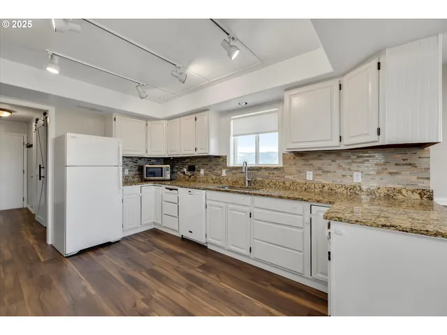 a kitchen with cabinets appliances wooden floor and a window