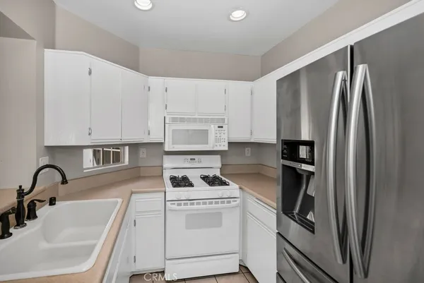 a kitchen with stainless steel appliances kitchen island granite countertop a refrigerator and a sink