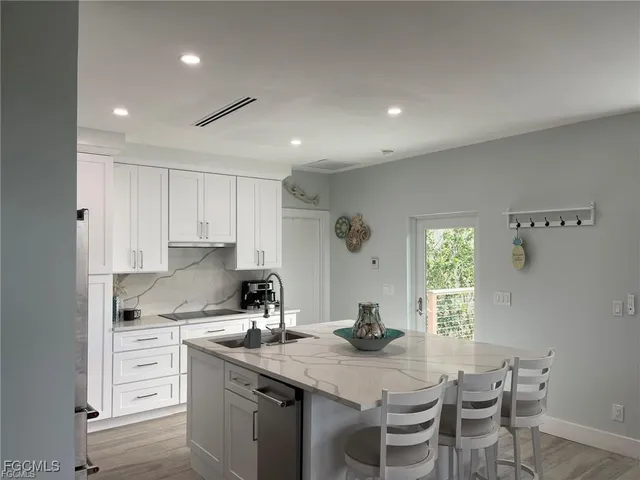 a kitchen with white cabinets and sink