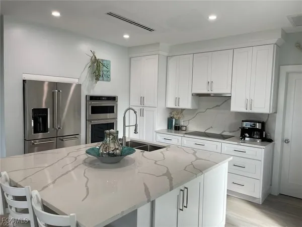 a kitchen with kitchen island granite countertop a sink cabinets and stainless steel appliances