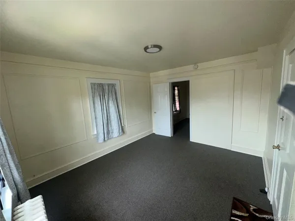 a view of an empty room with closet and a window