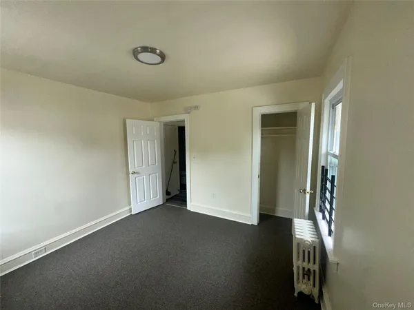 an empty room with wooden floor and windows with curtains