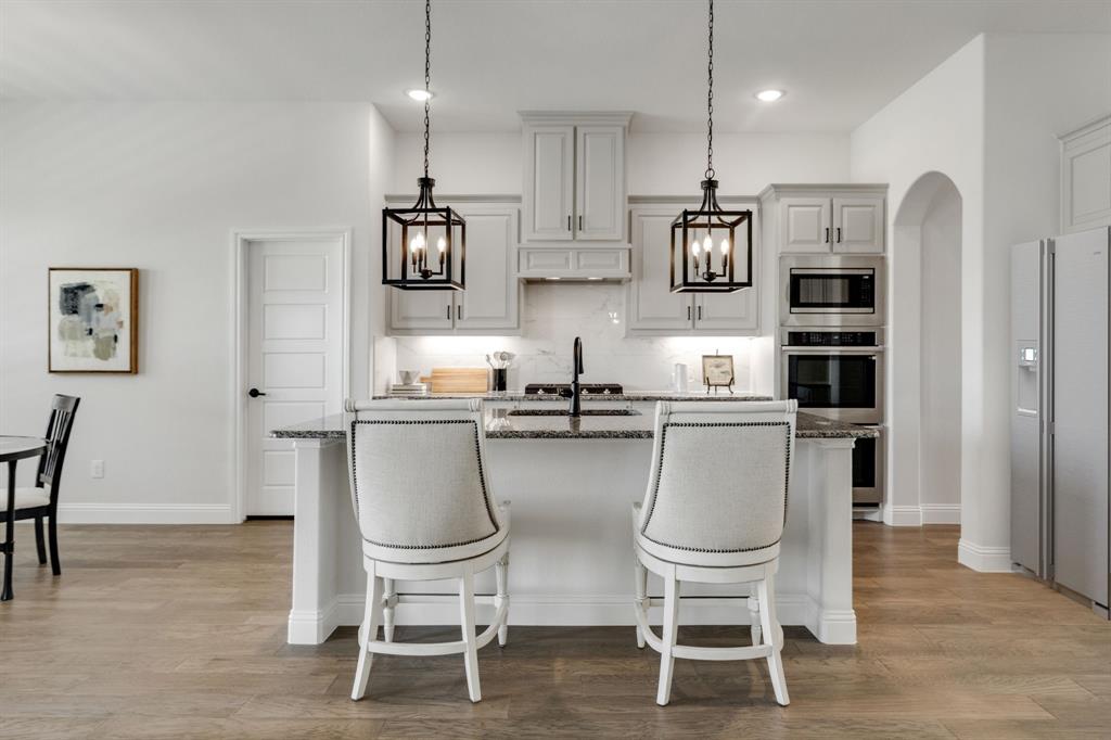 707 Soprano Drive Forney, TX 75126 - Photo 12 of 37 a kitchen with stainless steel appliances granite countertop a dining table chairs and a refrigerator