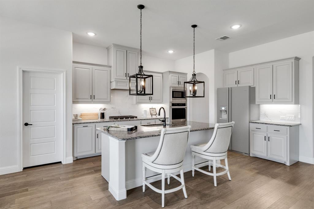 707 Soprano Drive Forney, TX 75126 - Photo 13 of 37 a kitchen with white cabinets and stainless steel appliances