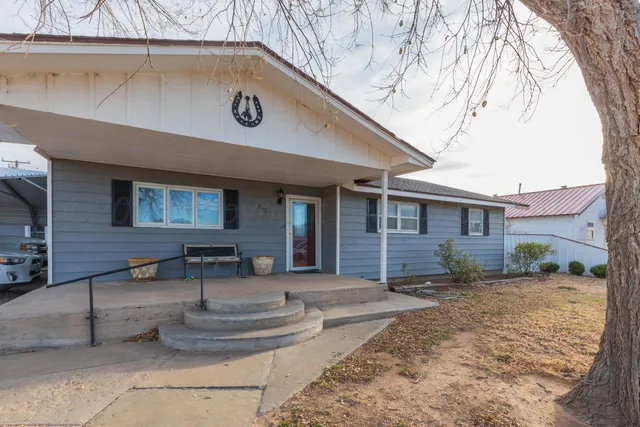 a view of a house with a yard and large tree