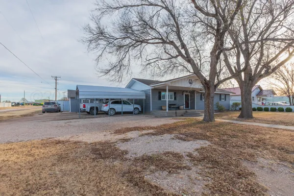a view of a house with a yard and large tree