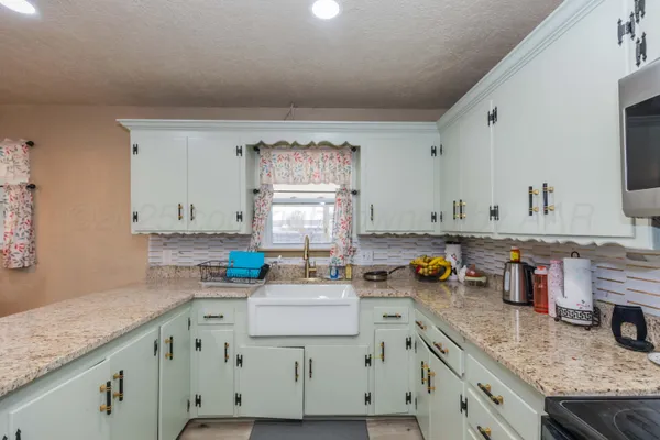 a kitchen with granite countertop a sink a stove and cabinets