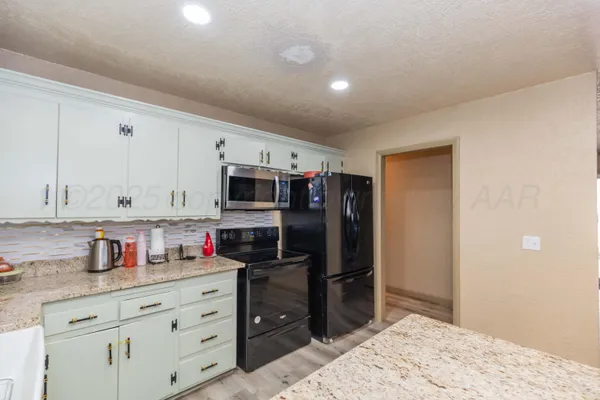 a kitchen with granite countertop a refrigerator and cabinets