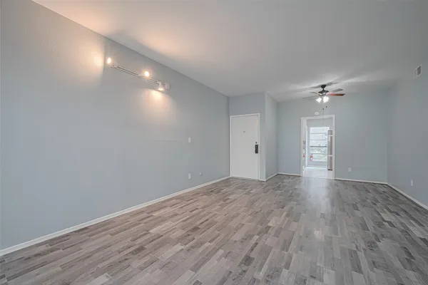 a view of empty room with wooden floor and fan