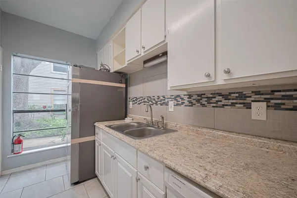 a kitchen with granite countertop a sink and a refrigerator