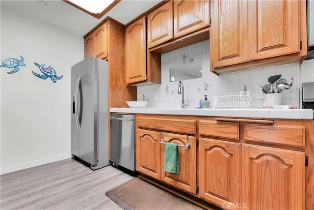 a kitchen with stainless steel appliances granite countertop a refrigerator a sink and dishwasher with wooden floor