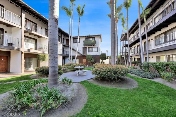 a front view of a brick house with a yard and potted plants