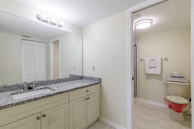 a bathroom with a granite countertop sink a toilet and a mirror