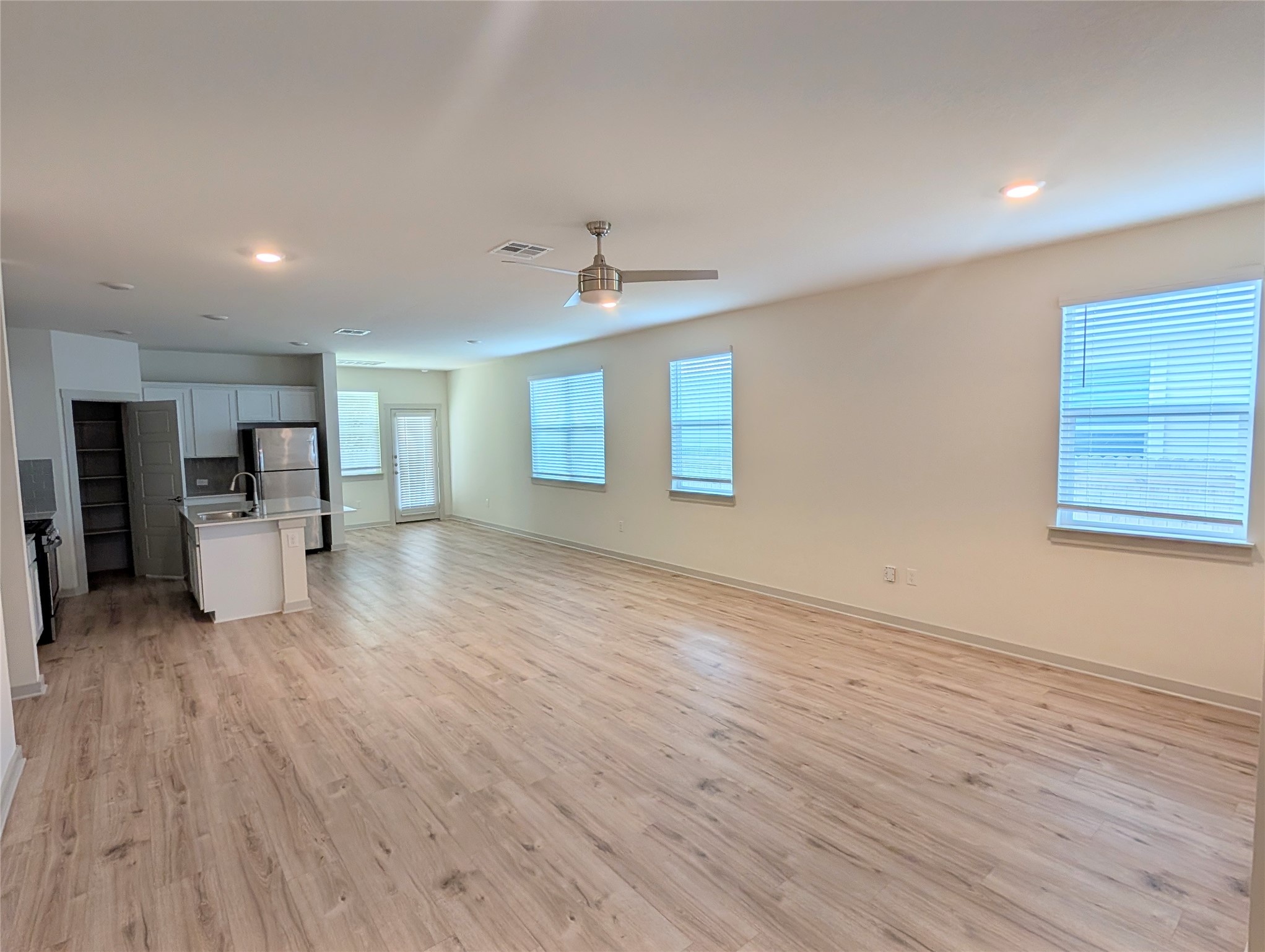 261 Century Plant Road Leander, TX 78641 - Photo 6 of 25 An open-concept layout showcases light wood flooring, seamlessly connecting the living area to a compact kitchen.