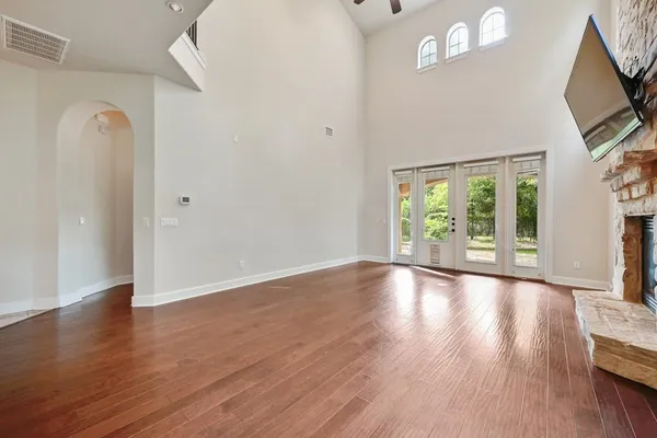 an empty room with wooden floor closet chandelier fan and windows