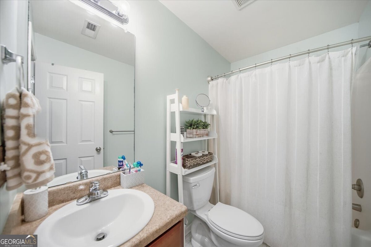1201 Pendley Point Hampton, GA 30228 - Photo 20 of 23 a bathroom with a sink a toilet and shower curtain