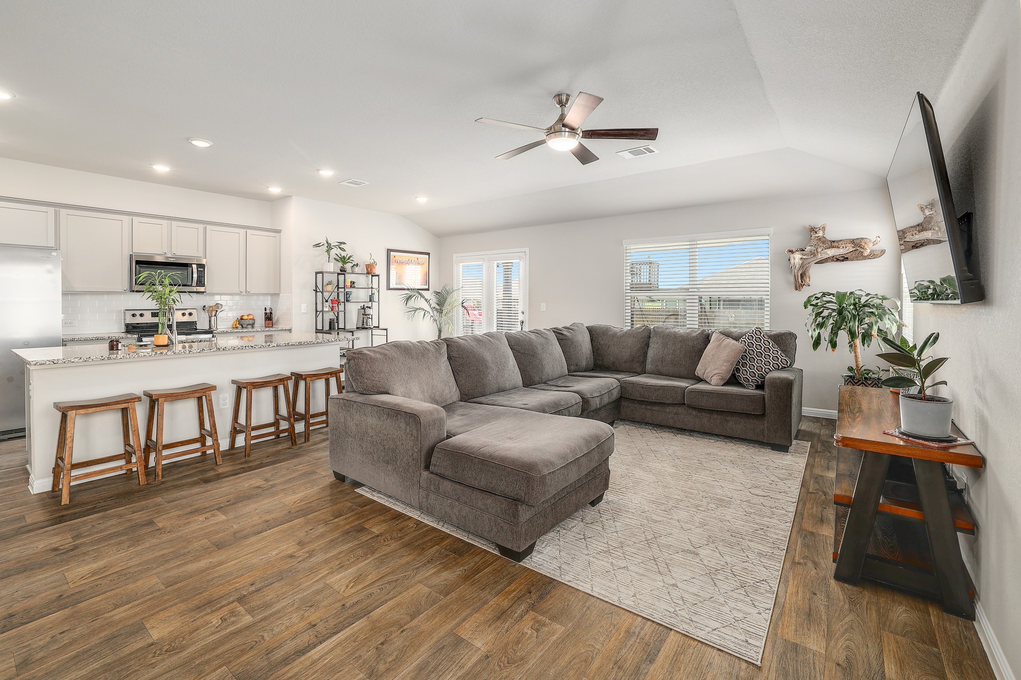 413 Hunter Loop Bertram, TX 78605 - Photo 3 of 27 An open concept living area boasts a kitchen with granite counters and rich vinyl plank flooring.