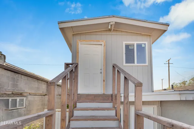 an empty room with a chandelier fan and windows