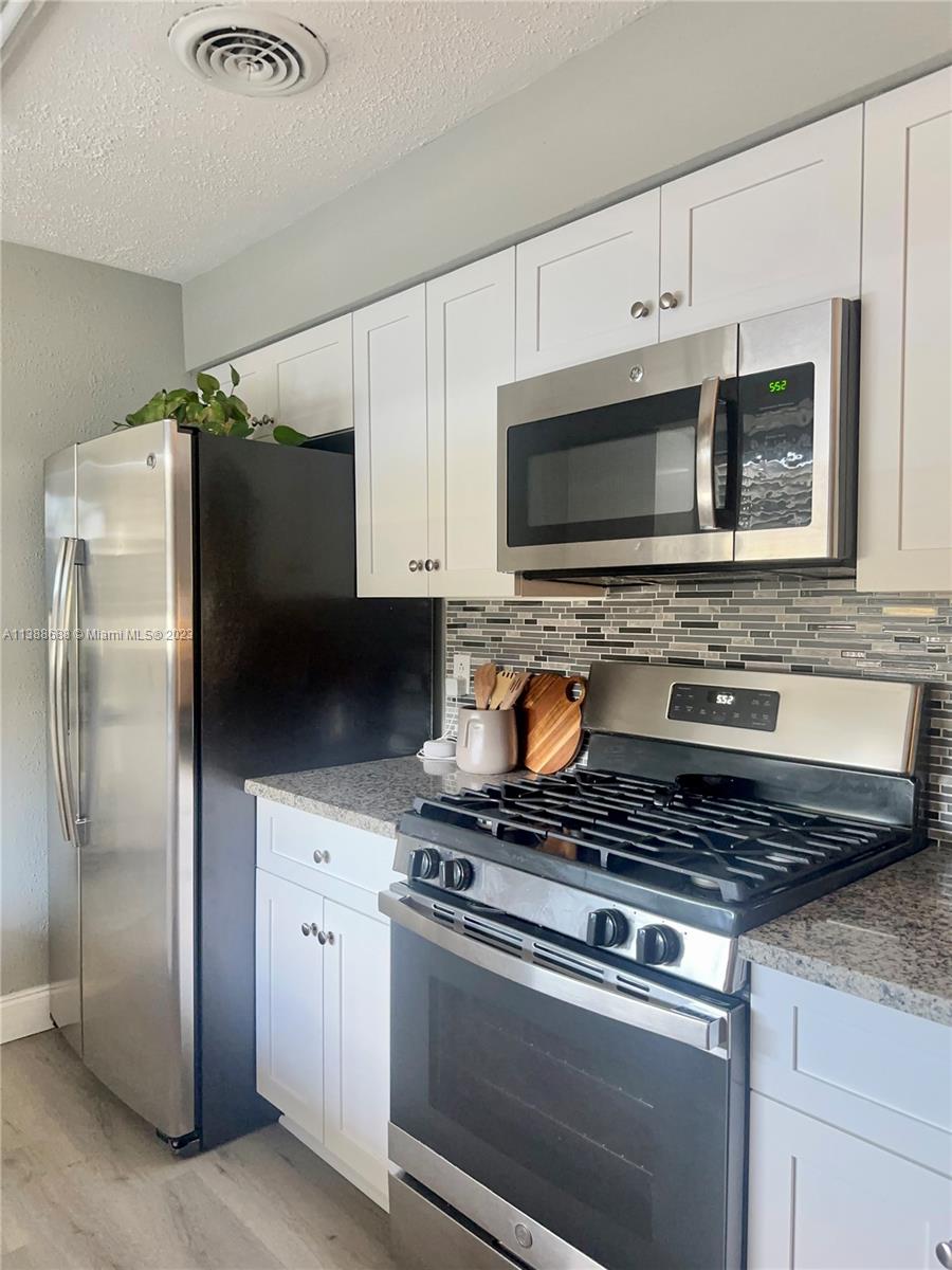 300 E Circle Jupiter, FL 33458 - Photo 9 of 28 a kitchen with granite countertop a refrigerator stove and microwave