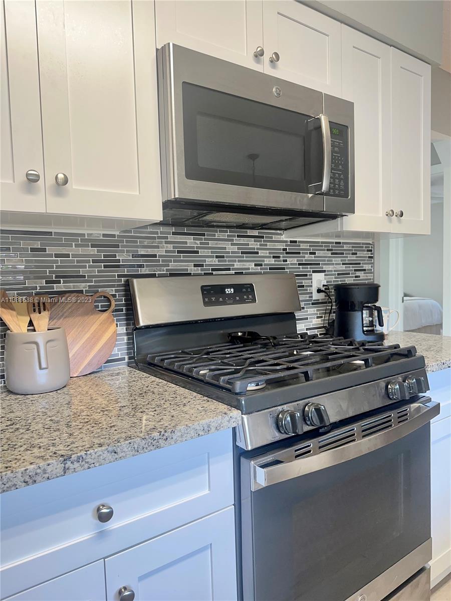 300 E Circle Jupiter, FL 33458 - Photo 10 of 28 a kitchen with granite countertop a stove and a microwave