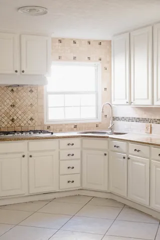 a bathroom with granite countertop white vanity white cabinets and a sink