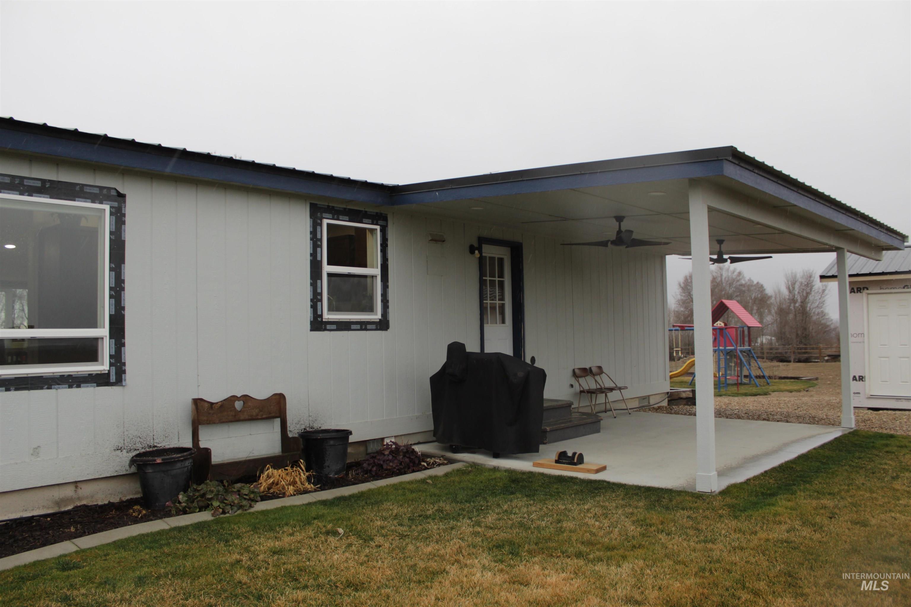 27520 Pearl Road Parma, ID 83660 - Photo 23 of 29 Rear view of house featuring a playground, a yard, ceiling fan, and a patio area