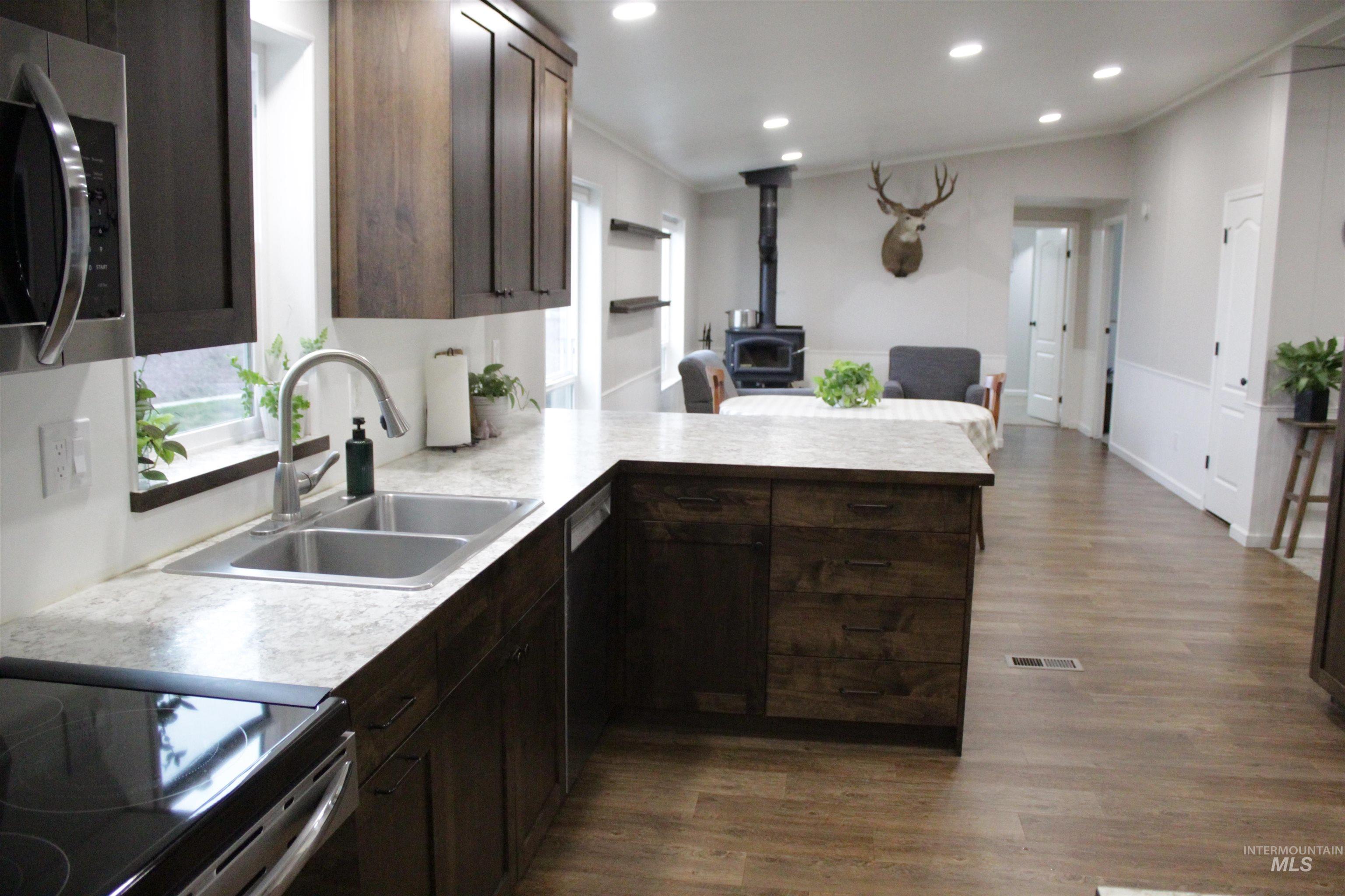 27520 Pearl Road Parma, ID 83660 - Photo 29 of 29 Kitchen with dark wood finish cabinets, a wood stove, stainless steel appliances, a peninsula, and open floor plan