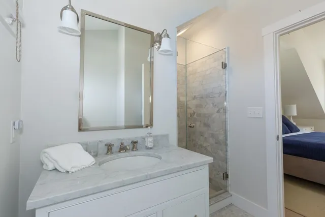 a bathroom with a granite countertop sink a mirror and shower