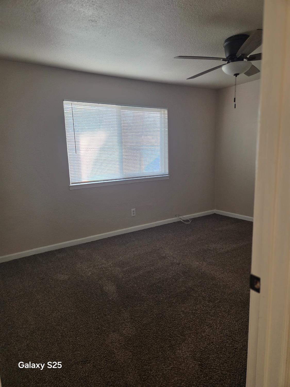 230 Tim Bell Road Waterford, CA 95386 - Photo 13 of 18 unfurnished room featuring dark carpet, a textured ceiling, and a ceiling fan