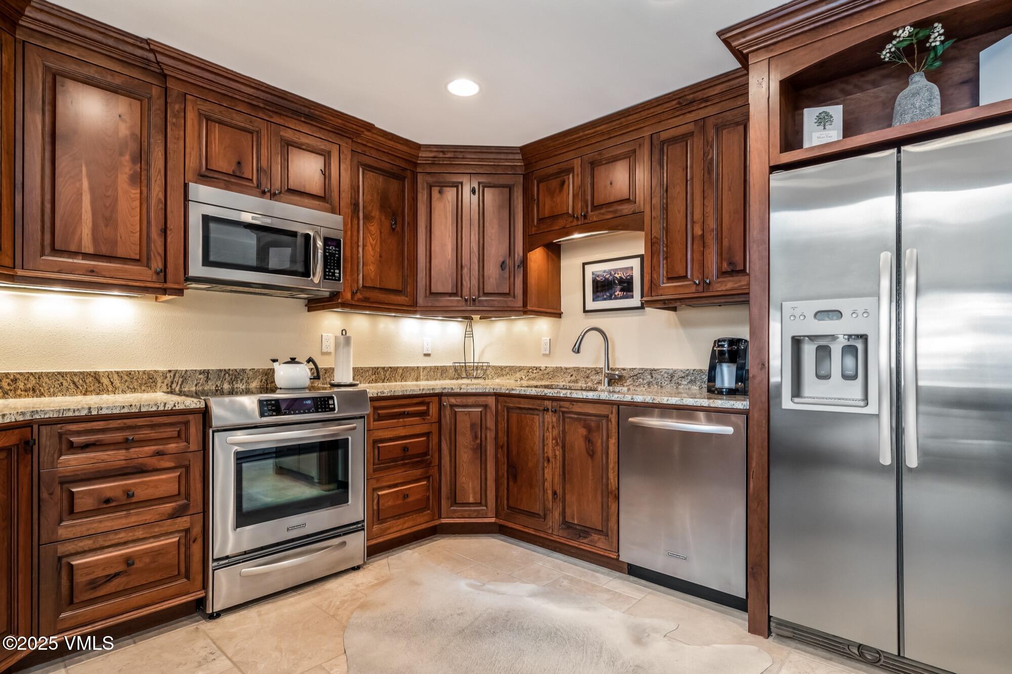 945 Red Sandstone Road, Unit A5 Vail, CO 81657 - Photo 15 of 38 a kitchen with granite countertop wooden cabinets stainless steel appliances and a window