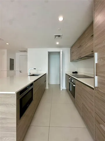 a large white kitchen with stainless steel appliances kitchen island granite countertop a stove and a sink