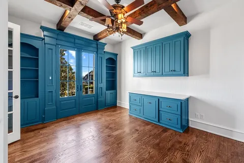 an empty room with wooden floor chandelier fan and windows