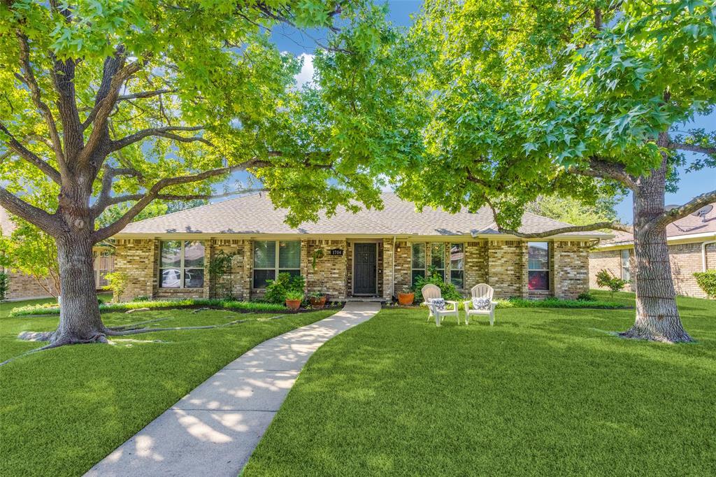 a front view of a house with a garden and trees