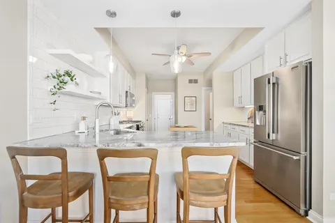 a kitchen with stainless steel appliances kitchen island granite countertop a refrigerator and a dining table