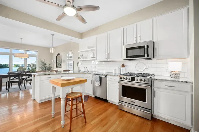 a kitchen with stainless steel appliances a stove a sink and white cabinets