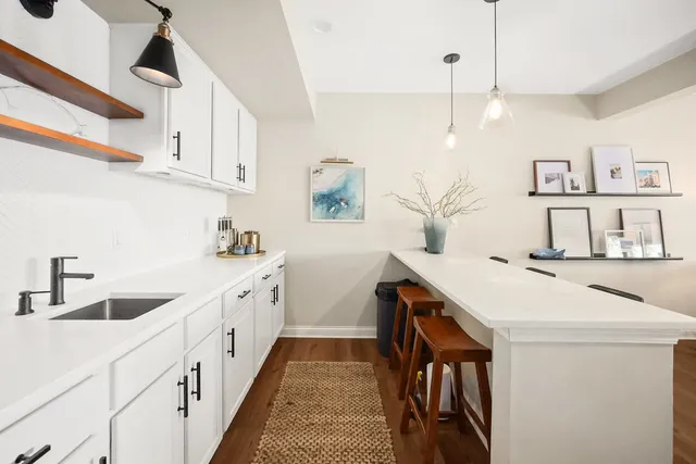 a living room with lots of white furniture and a wooden floor