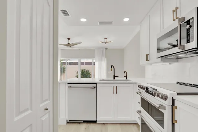 a kitchen with white cabinets and appliances