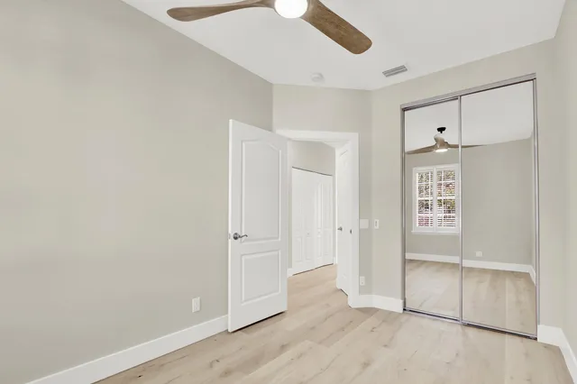 an empty room with wooden floor cabinet and windows