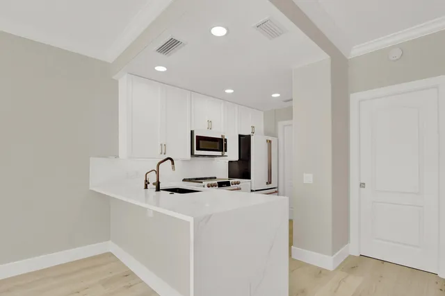 a kitchen with stainless steel appliances a sink a microwave a refrigerator and a counter top space