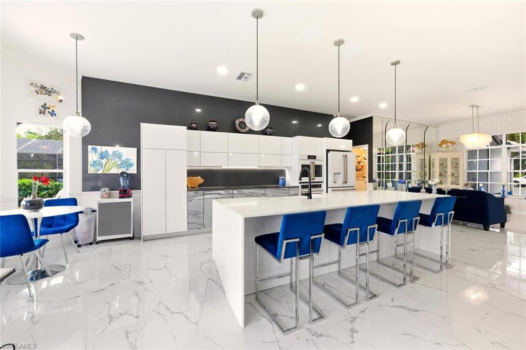 209 Countryside Drive Naples, FL 34104 - Photo 8 of 50 Kitchen with white cabinetry, decorative light fixtures, modern cabinets, a breakfast bar area, and a large island