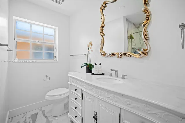 a bathroom with a granite countertop sink a toilet and a mirror