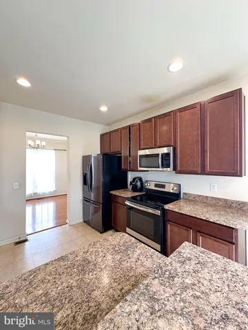 a kitchen with granite countertop a refrigerator and a stove top oven