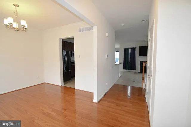 a view of a hallway with wooden floor and a bathroom