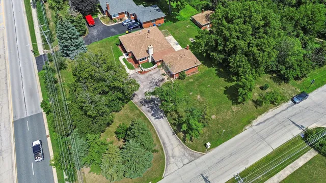 an aerial view of a house with a yard and trees all around
