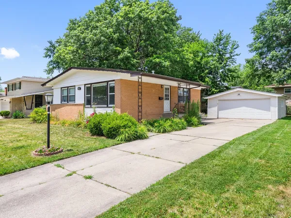 a front view of a house with a yard and potted plants